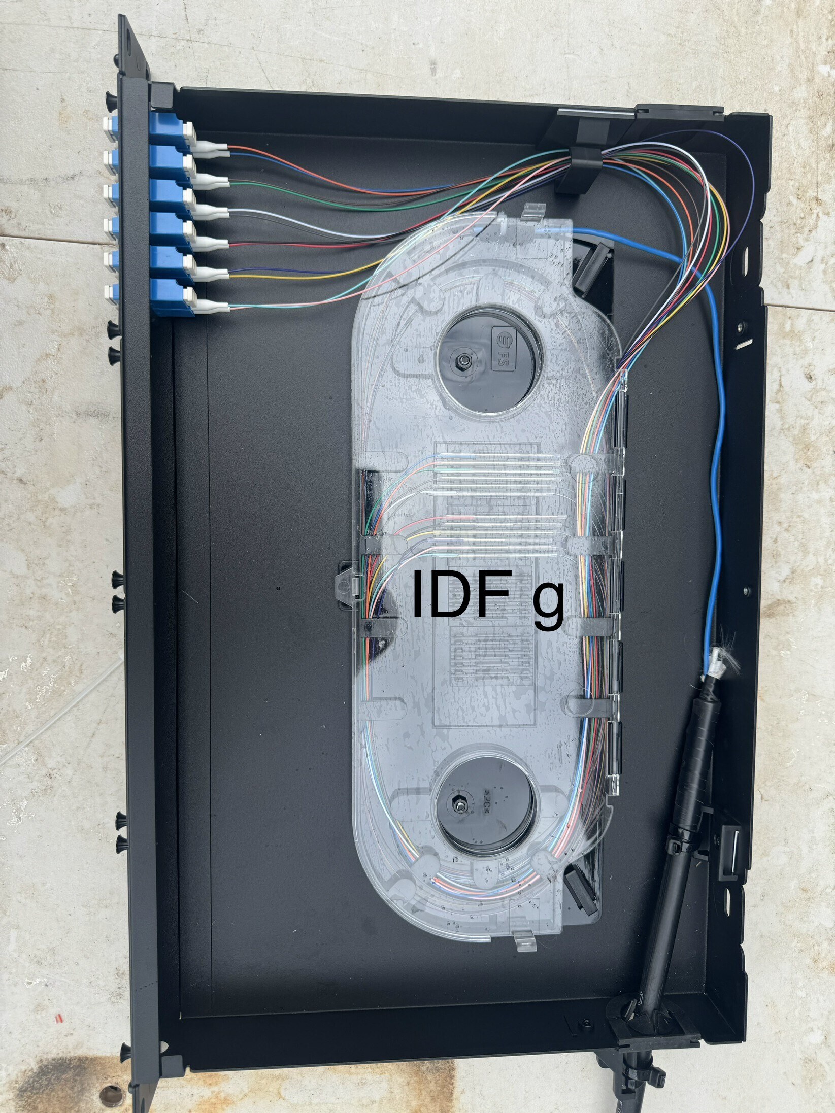 IDF fiber strands routed from adapters through a protected splice enclosure
