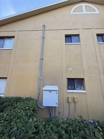 Exterior telecommunications enclosure connected by pathway conduit on a multifamily building