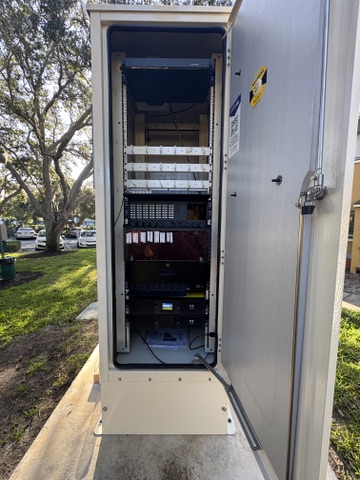 Open outdoor telecommunications cabinet with installed network and power equipment