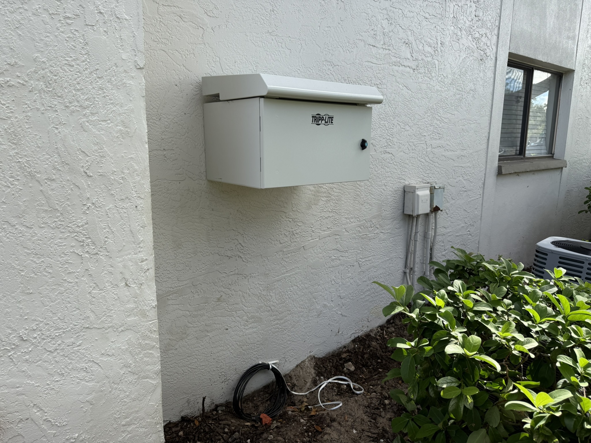 Building-mounted telecommunications enclosure on a multifamily building
