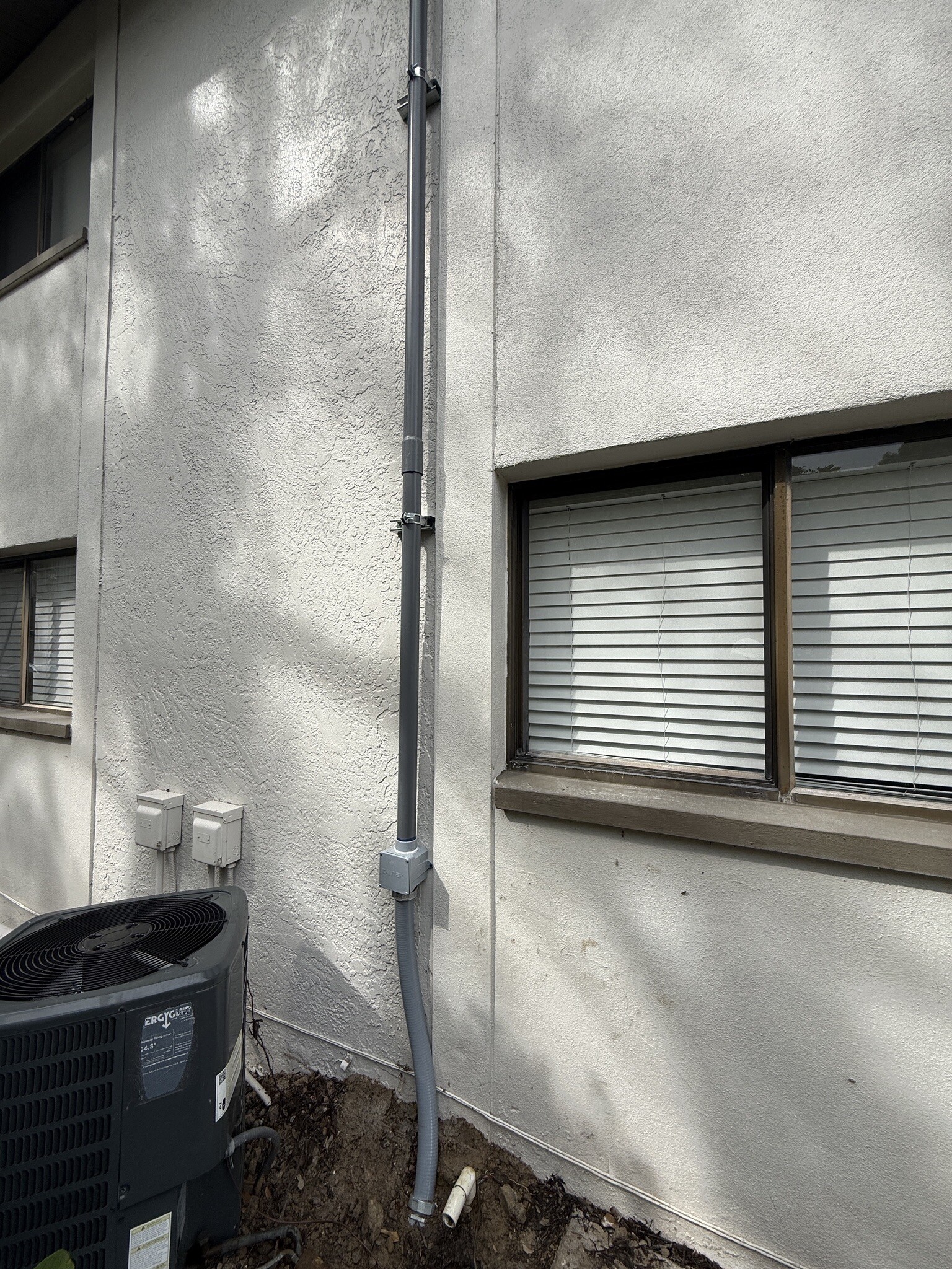 Exterior conduit pathway routed to a building-mounted telecommunications enclosure