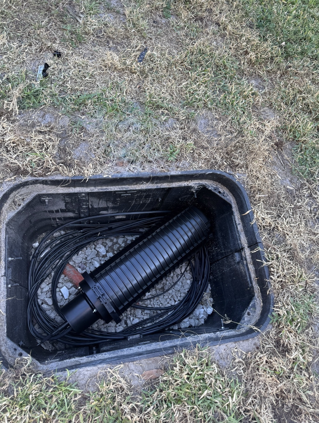 Underground telecommunications handhole with protected fiber enclosure